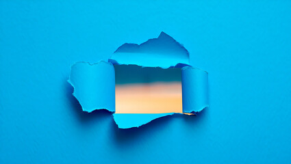 Torn blue paper revealing a serene sunset over a calm ocean horizon