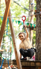 Little cute girl child having fun at adventure park. Kids climbing in a rope park. Children summer...