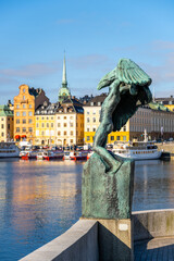 Wings - a bronze sculpture stands at Skeppsholmen Bridge with a view of colorful buildings and...