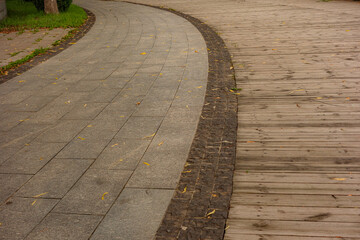 Wooden boardwalk, marble steps, asphalt road, and pedestrian walkway amidst vegetation