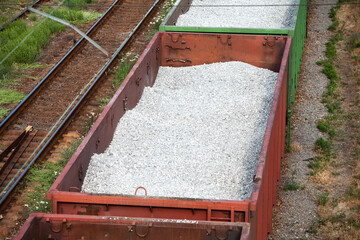 A train with open carriages transports titanium ore from a mining site to a loading port for...