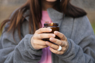 Teen girl holding candle outdoors in nature, peaceful mood and natural light.
