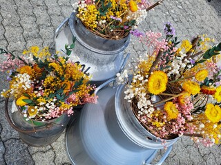 old milk kettles filled with colored dried flowers