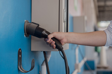 Hand is holding fast electric car charger green energy environment friendly driving vehicle...