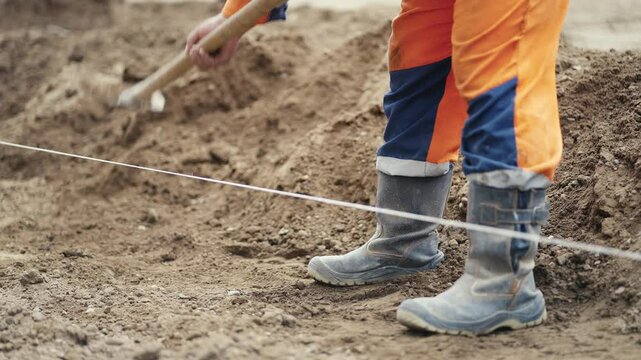 A diligent construction worker actively digging on a busy construction site while wearing essential safety gear