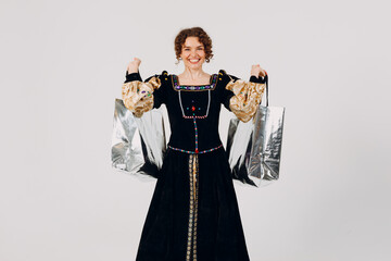 Young adult woman dressed in a medieval dress holding shopping bags in hands isolated white...