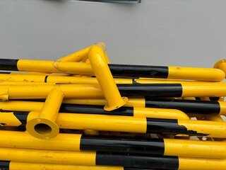 Stack of yellow and black safety steel pipes used for industrial protection or barriers. Scratches...