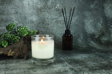 nice burning luxury aromatic scented candle glass is on stone table with a few rocks and background...