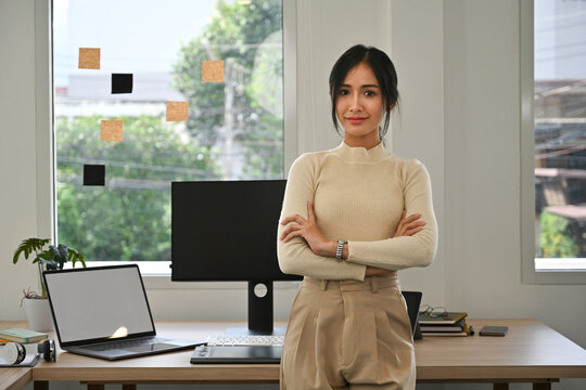 Portrait of Confident young Asian graphic designer standing with arms crossed in a bright modern studio - Powered by Adobe