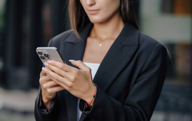 Hands of business woman using smartphone at city street