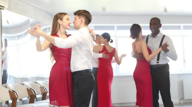Couple of young guy and young woman dancing waltz in studio