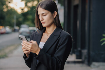 Business woman using smartphone at city street