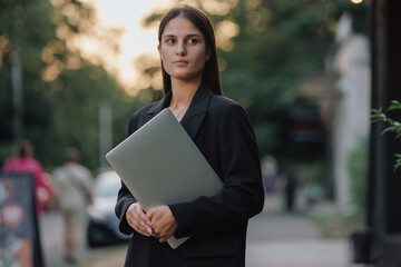 Woman in business suit holding laptop at the city