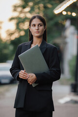 Woman in business suit holding laptop at the city