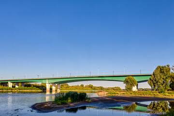 Warsaw, Poland - a long green Maria Skłodowska-Curie bridge with concrete pillars spans the...