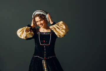 Portrait of a young aristocratic woman with headphones and touching head and dressed in a medieval...