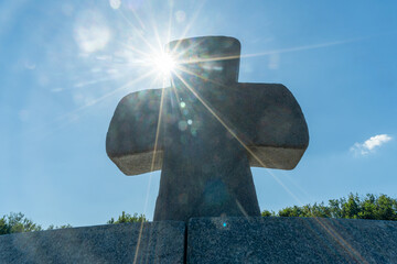A solitary stone cross on a hill bathed in sunlight represents the enduring spirit of sacrifice and...
