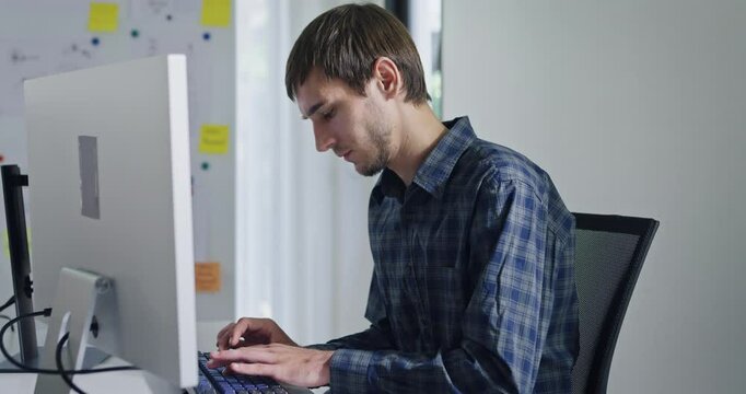 Portrait confident smiling male programmer working with robotics code AI software and looking at camera in tech office. Artificial intelligence dashboard, robotics, user interface, machine learning.
