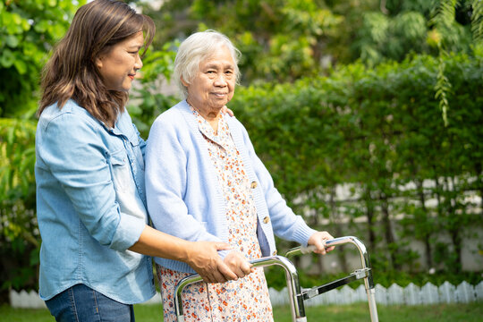 Caregiver help and care Asian senior woman patient walk with walker in park.
