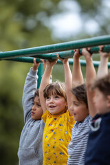 Obraz premium Kids on monkey bars, reaching for success. Group of children playing and having fun. Childhood adventure, play, friendship and active lifestyle concept.