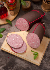 Beautiful meat sausage on a wooden table among greens, vegetables and spices