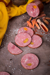 Beautiful meat sausage on a wooden table among greens, vegetables and spices