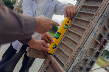 Construction contractor, checking and recording construction details using tape measure and not...