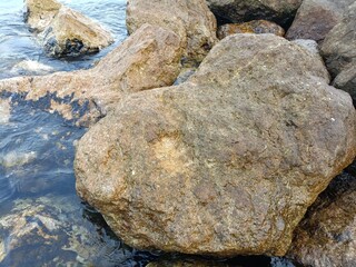 Large, rounded rocks positioned near the water's edge, displaying varied textures and colors.