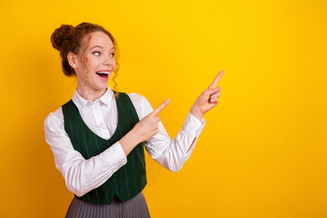 Smiling young student gesturing with hands on vibrant yellow background, promoting learning,...