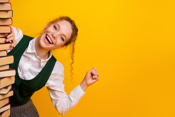 Cheerful Female Student Smiling While Studying with Books in Educational Setup with Vibrant Yellow...