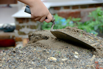 Hand Using Trowel with Mortar Pile for Construction Work