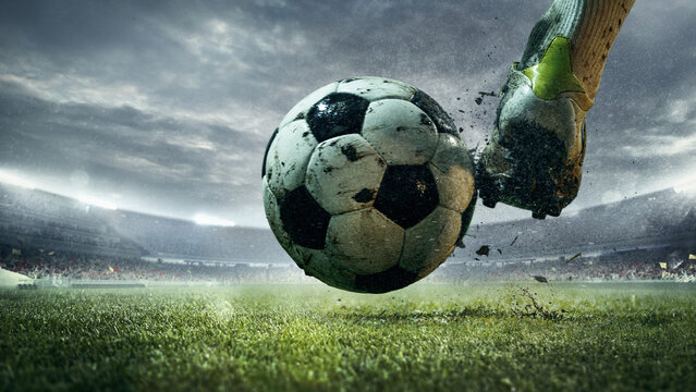 Muddy football being kicked on grass field under cloudy sky in 3D stadium. Concept of energy management and sustainable motivation