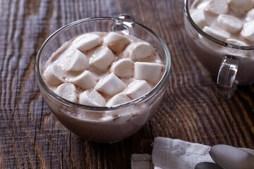 Hot chocolate with marshmallows in glass mug on wooden background