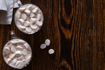 Hot chocolate with marshmallows in glass mug on wooden background