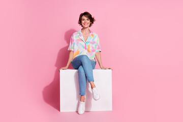 Full body portrait of nice young woman sit podium empty space wear shirt isolated on pink color...