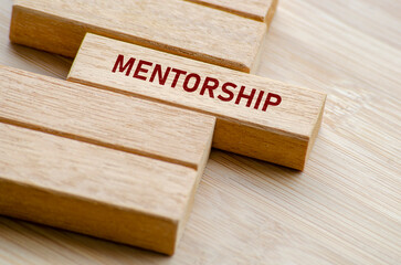 Mentorship word on wood blocks, capturing the core value of guiding others through experience,...