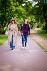 Visually impaired woman walking with female friend in the city park