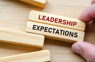 Leadership expectation message on wooden blocks held by hand, symbolizing the pressure and responsibility placed on those who take the lead in any organization