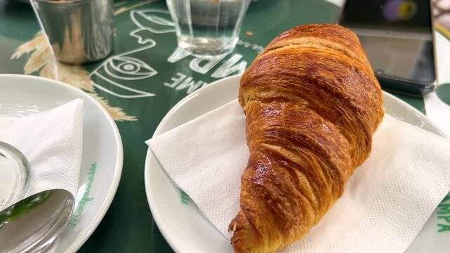 Breakfast in Paris. Flat white coffee and fresh croissant on the terrace of a cafe at place Edgar Quinet, Montparnasse district, Paris, France.