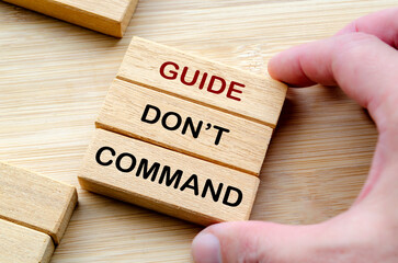 Guide, do not command phrase on wooden blocks, emphasizing mentorship, encouragement, and empowerment over authoritarian control