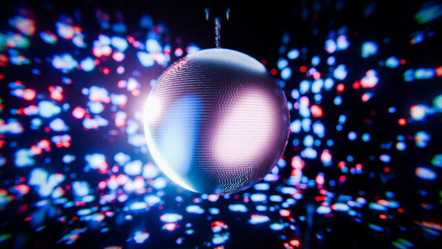 Shiny disco ball rotating under colorful spotlights in nightclub