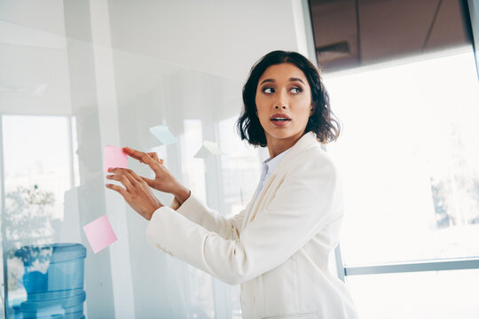 Confident businesswoman organizing ideas with sticky notes in a modern office workspace