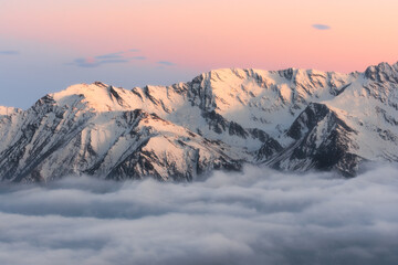 Sunset in the high mountains with a carpet of clouds underneath