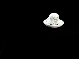 white ceramic mug with a vintage Paris design, placed on a matching saucer against a black fabric...