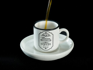 Pouring Coffee into Vintage Paris Mug on Black Background
