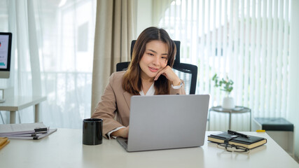 Smiling businesswoman focused on her computer screen during work hours.