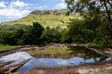 Reflections of the Drakensberg mountains in South Africa, within a shallow pool, on a clear and sunny day.