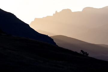 The last light of the setting sun shining through a valley and mountains of the Central Drakensberg...