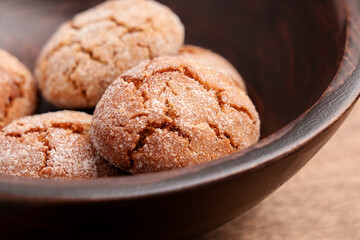 Baked fresh sugar ginger cracked cookies in wooden bowl on table
