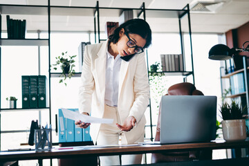 Confident businesswoman in a professional office setting managing tasks efficiently with phone and...
